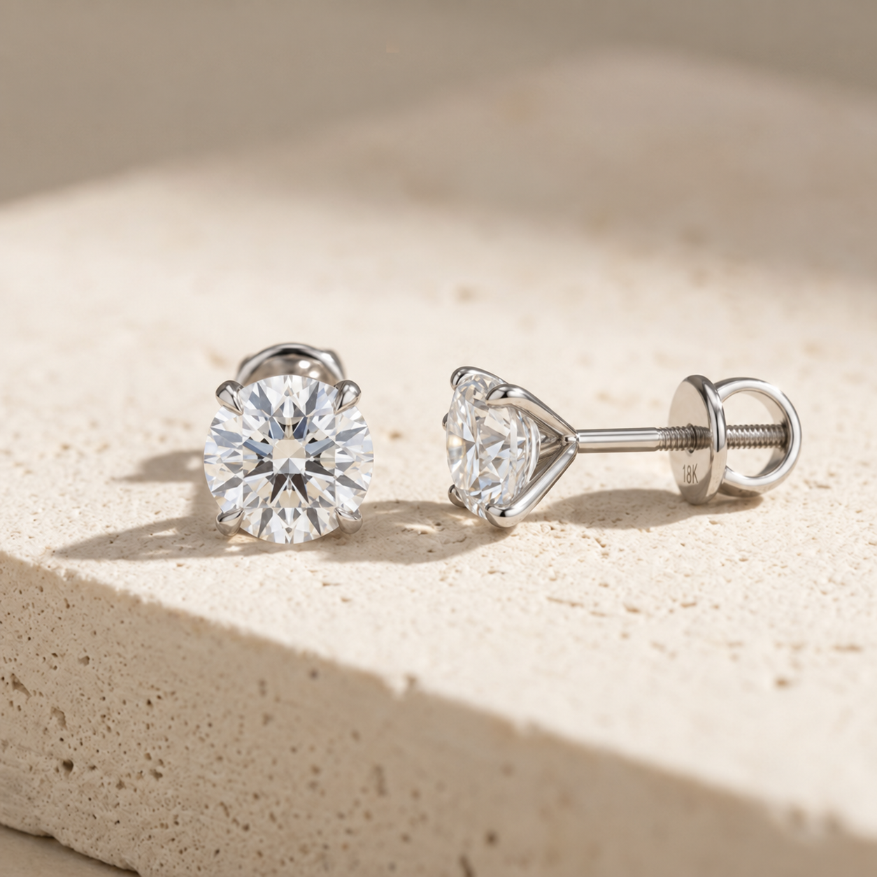 Front and profile view of the RW four-claw flower-style diamond studs with screw-back fastening on cream concrete