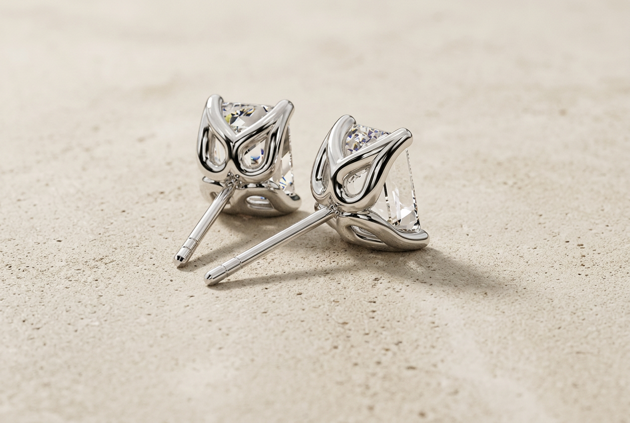 Profile of The Manhattan diamond studs showing their open four-claw settings and posts on cream concrete
